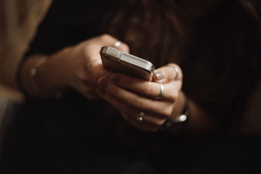 Person reading a webtoon on a smartphone while comparing different comic editions.